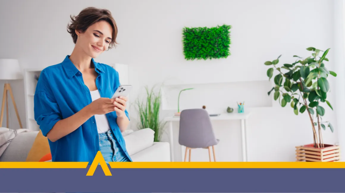 Uśmiechnięta kobieta korzystająca z telefonu w domowym biurze